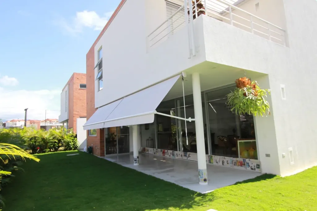 Baneta Proyectante con los brazos a 135 grados dando sombra al ventanal de una vivienda