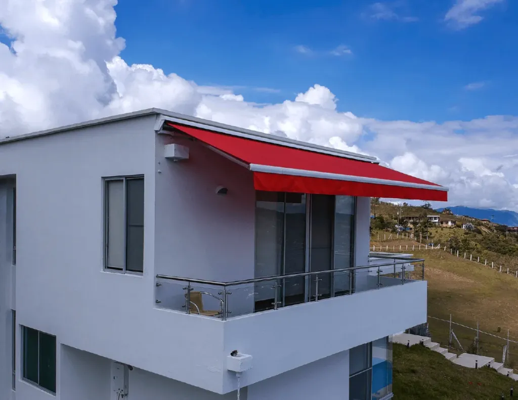 Baneta Proyectante en lona roja instalada sobre el balcón de una vivienda de dos plantas