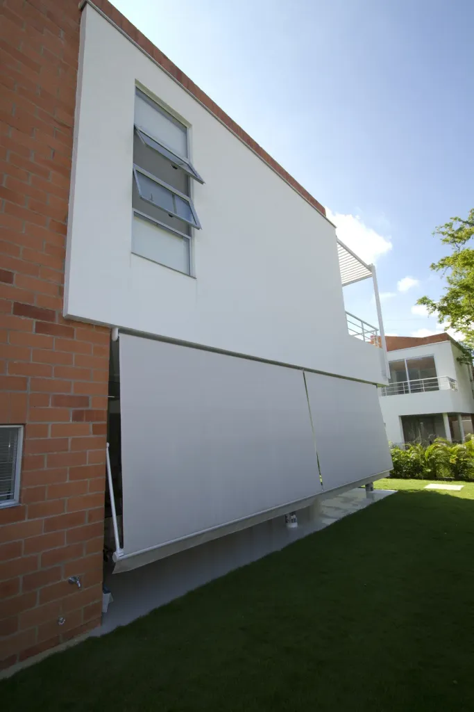 Dos Banetas Proyectantes en línea protegiendo el corredor lateral de una vivienda en ladrillo