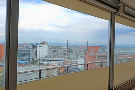 FlexiZipp con las lonas recogidas sobre la baranda de vidrio de una terraza, dejando la vista libre