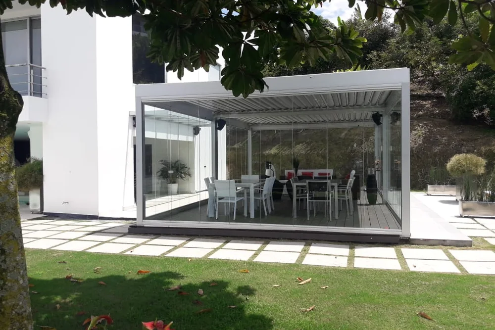 Pérgola cerrada en su perímetro con Slidinglass, vista desde el jardín de una casa