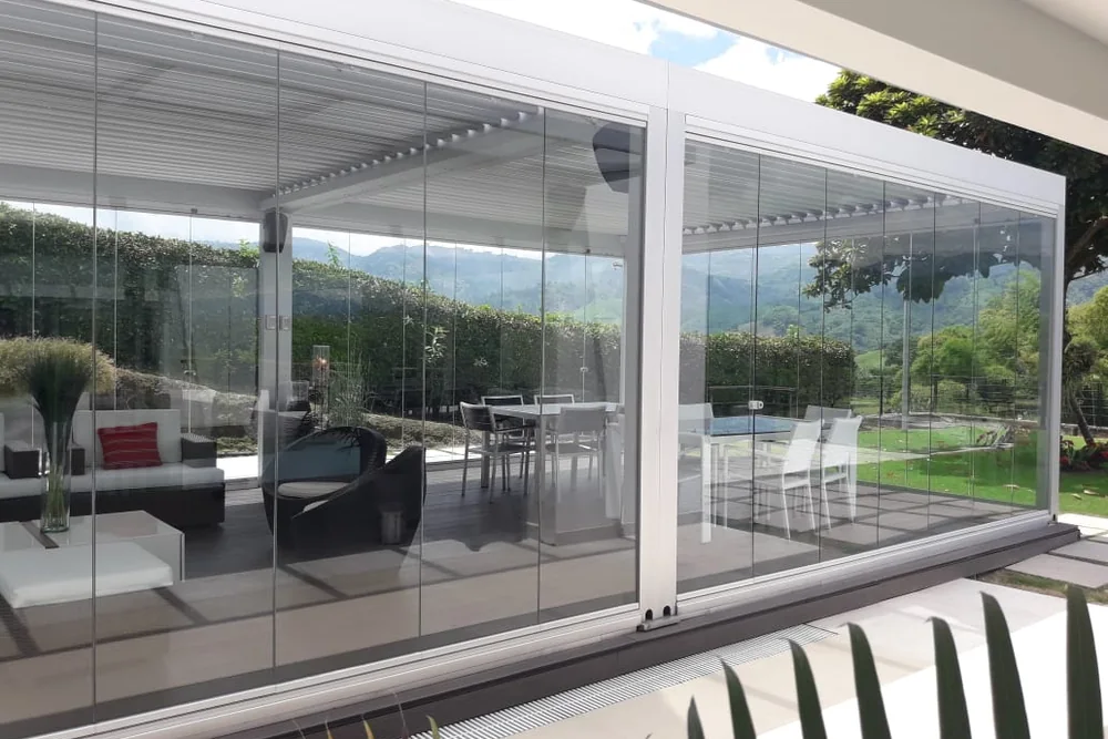 Sala exterior cerrada con Slidinglass, con los paneles de vidrio corridos y la montaña al fondo