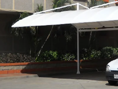 Cubierta de lona tensada sobre el parqueadero de un edificio, sostenida por columnas metálicas