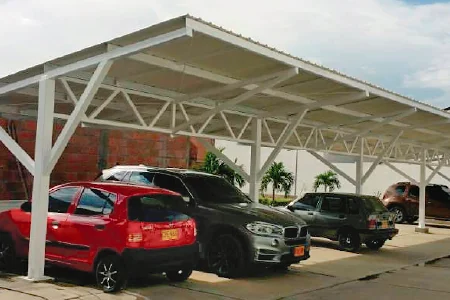 Cubrimiento para parqueadero con estructura metálica a dos aguas sobre cerchas, cubriendo varios vehículos en un conjunto residencial