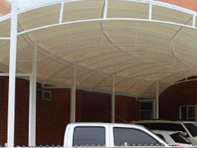 Panel curvo translúcido de la cubierta de un parqueadero, apoyado sobre arcos metálicos