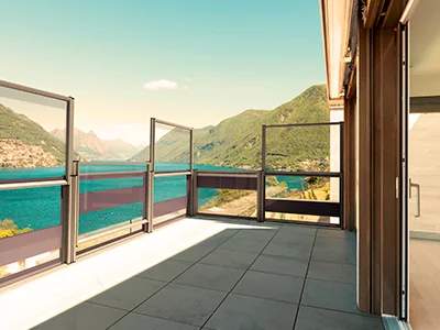 Paneles FlexiWind a distinta altura sobre la baranda de una terraza, con el lago al fondo