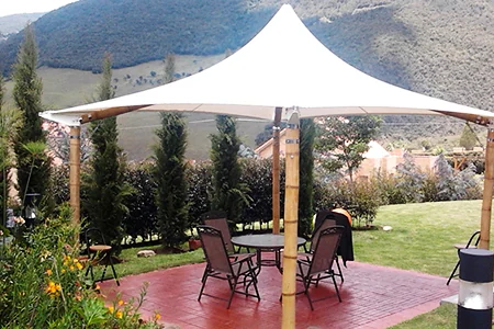 Membrana tipo kiosco con mástiles forrados en guadua sobre la terraza de un jardín residencial