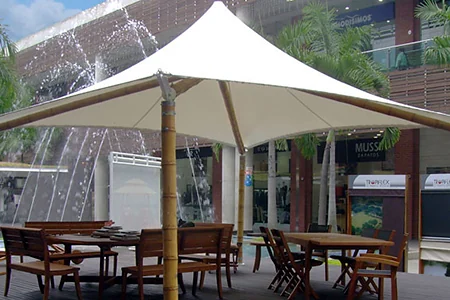 Membrana tipo kiosco sobre la terraza de mesas de un centro comercial, junto a la fuente