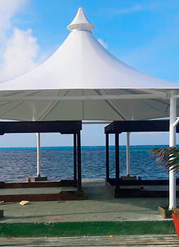 Membrana tipo kiosco sobre una terraza de muelle frente al mar