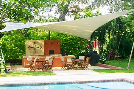 Membrana tipo pañuelo tensada sobre la zona de asados de una casa, junto a la piscina