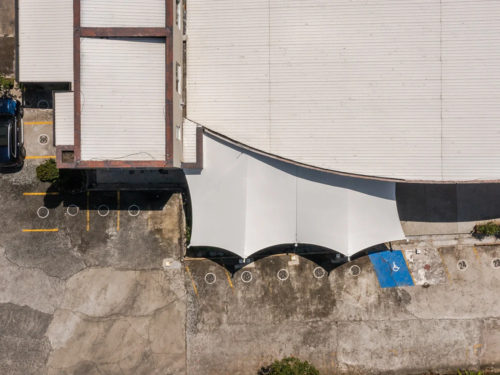 Vista aérea de una membrana tipo pañuelo tensada contra la fachada curva de un edificio