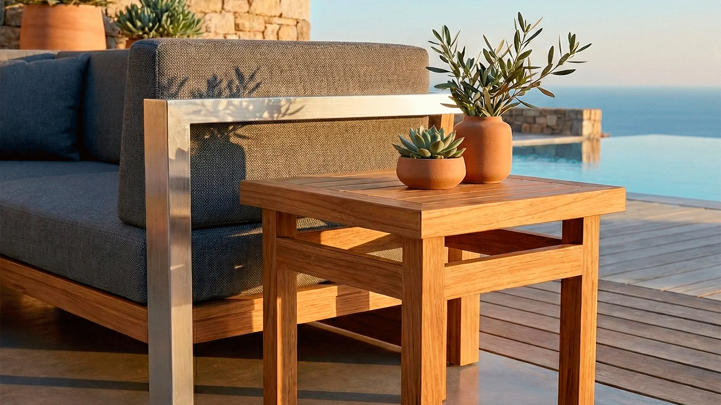 Mesa auxiliar Sakata en madera teca junto a una poltrona, en el jardín