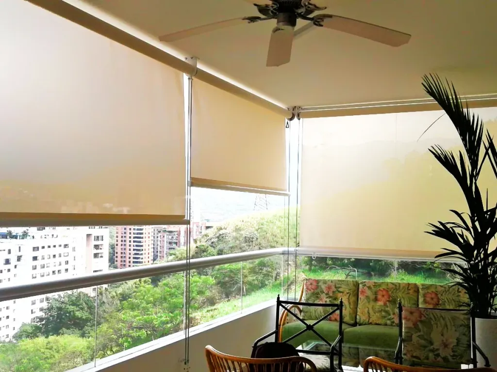 Toldos verticales Baneta Vertical de lona beige como parasol en el balcón de un apartamento con vista a la ciudad