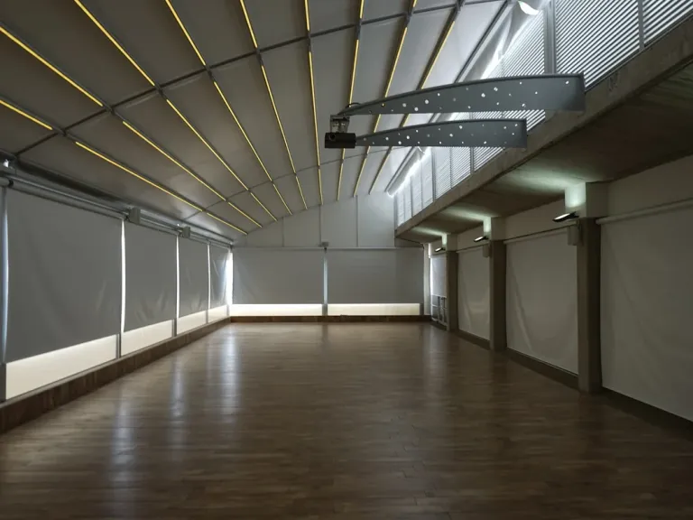 Iluminación LED integrada en los perfiles curvos de una pérgola retráctil PergoDom, vista desde el interior