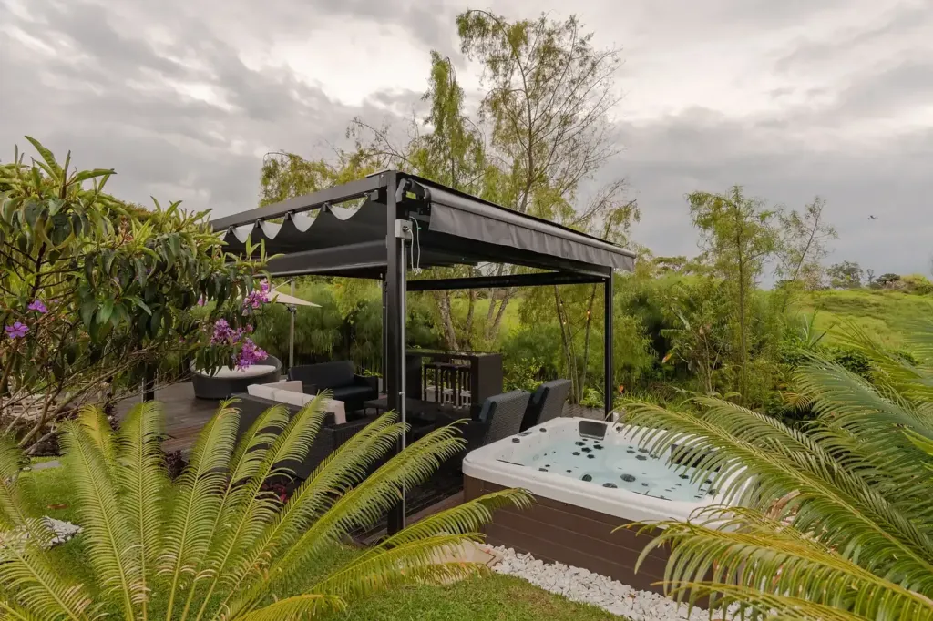 pérgola PergoFlex junto al jacuzzi y el jardín, con la lona a medio recoger
