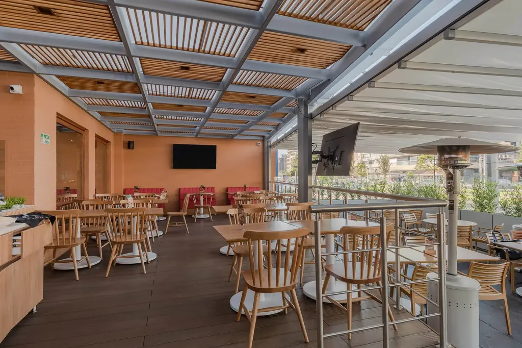detalle de la pérgola fija: retícula metálica con paneles de listones de madera sobre la tarima
