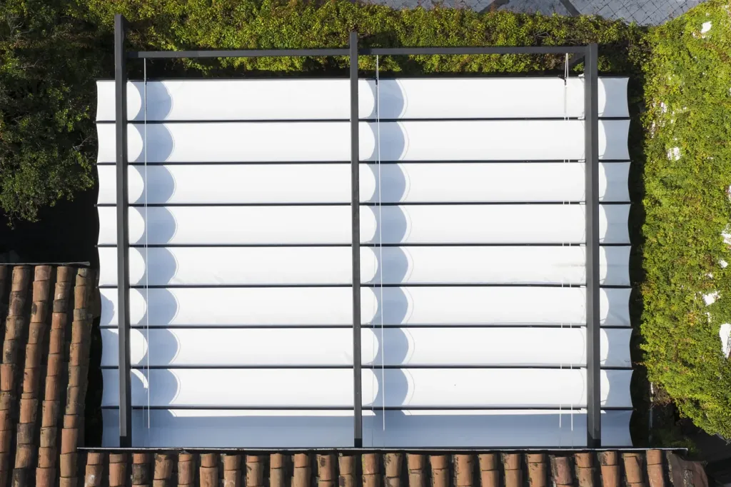 detalle cenital de los dos módulos de lona plegable del PergoFlex desplegados entre los muros verdes