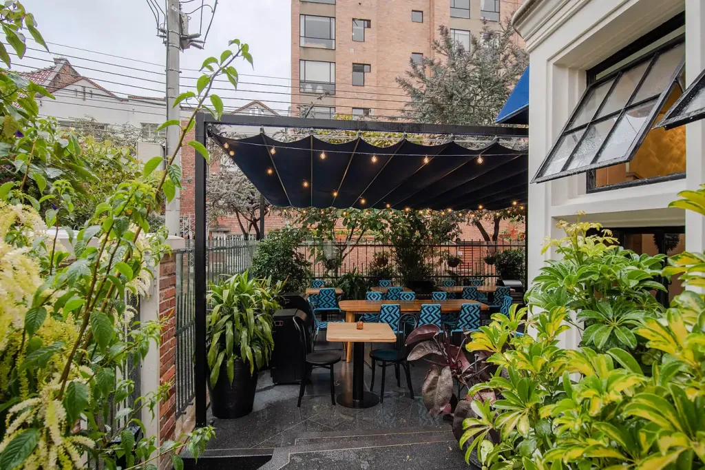 el patio cubierto por el PergoFlex visto entre la vegetación del jardín