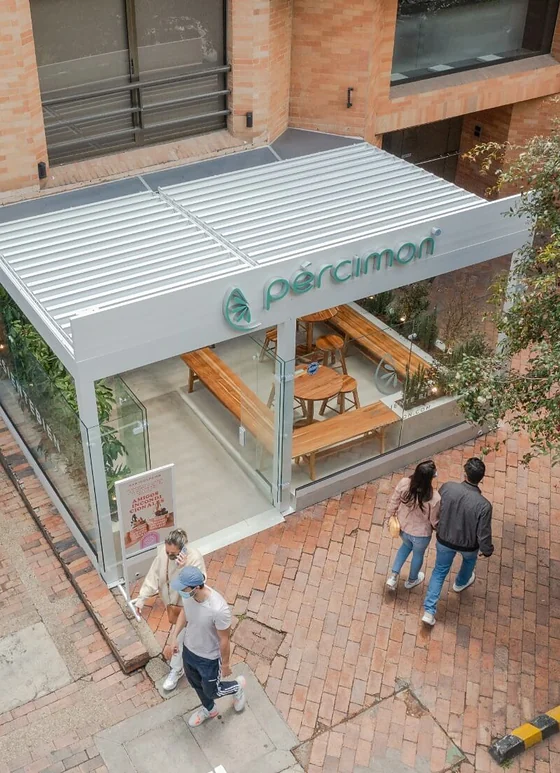 Pérgola bioclimática PergoLam de lamas de aluminio sobre la terraza de un local comercial