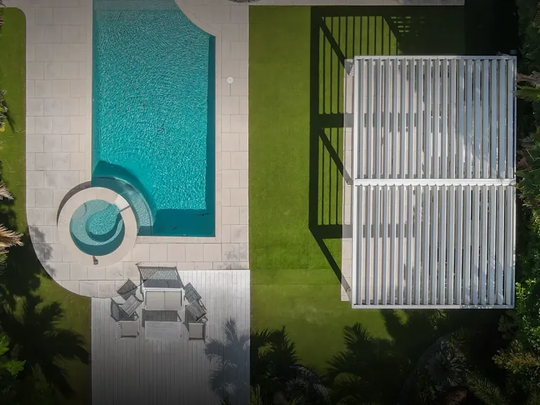 Vista cenital de las lamas orientables de una pérgola bioclimática PergoLam abiertas sobre el patio de una casa