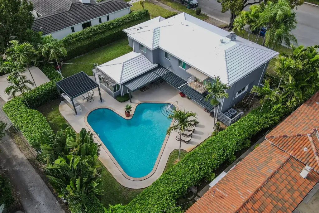 Pérgola bioclimática PergoLam en el patio de una casa residencial con piscina, vista desde un dron