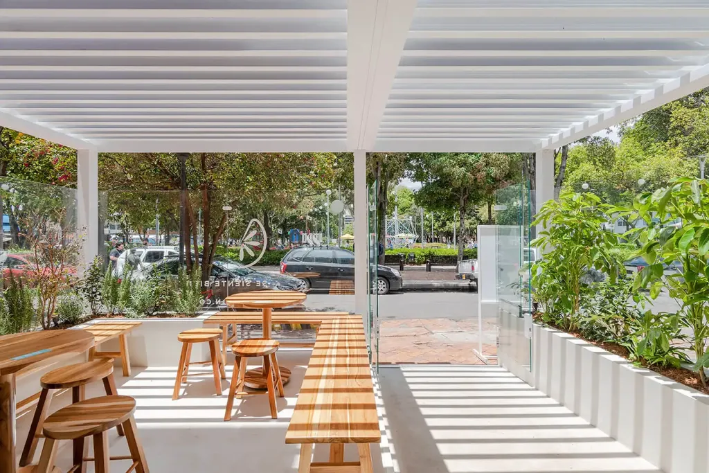 Pérgola bioclimática PergoLam con las lamas abiertas sobre la terraza de una cafetería
