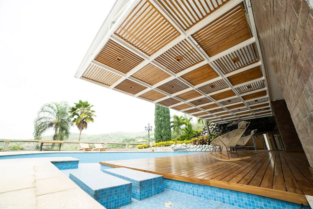 entramado de listones de teca de la pérgola fija visto desde la piscina de la casa campestre
