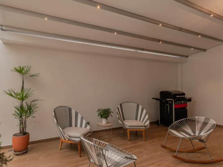 Patio cubierto con pérgola de lona e iluminación LED empotrada en las vigas de aluminio