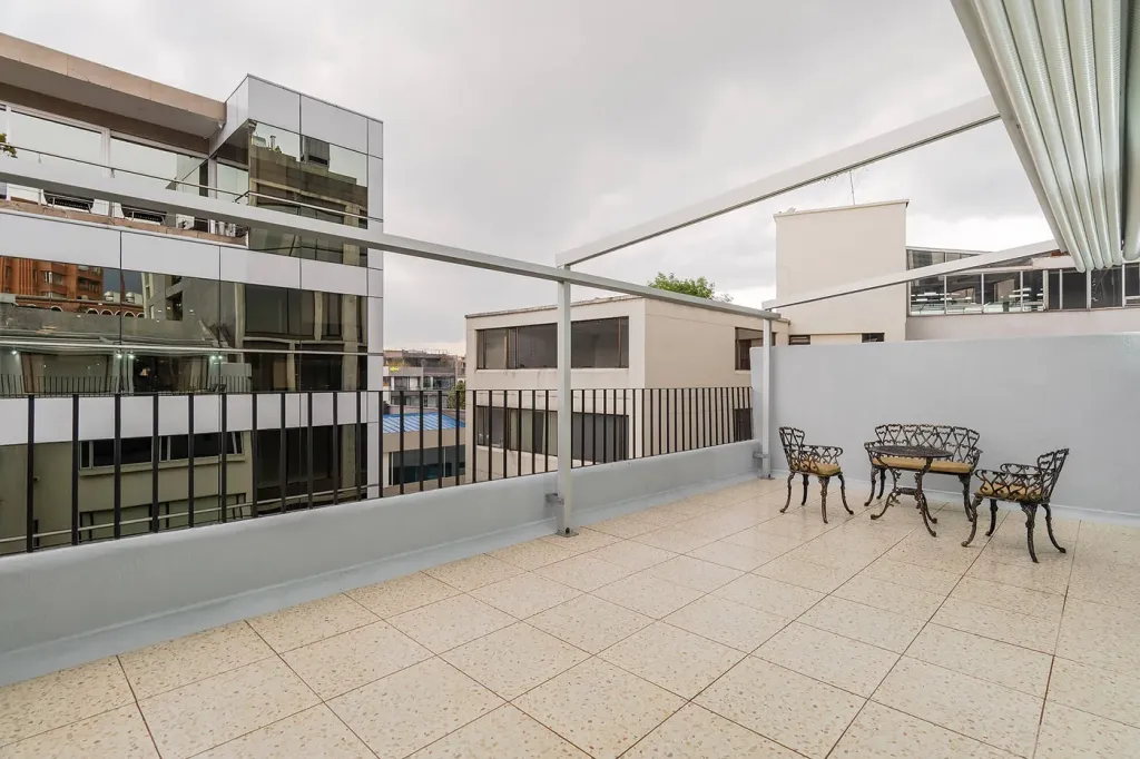balcón de un apartamento con la pérgola retráctil recogida y la ciudad al fondo