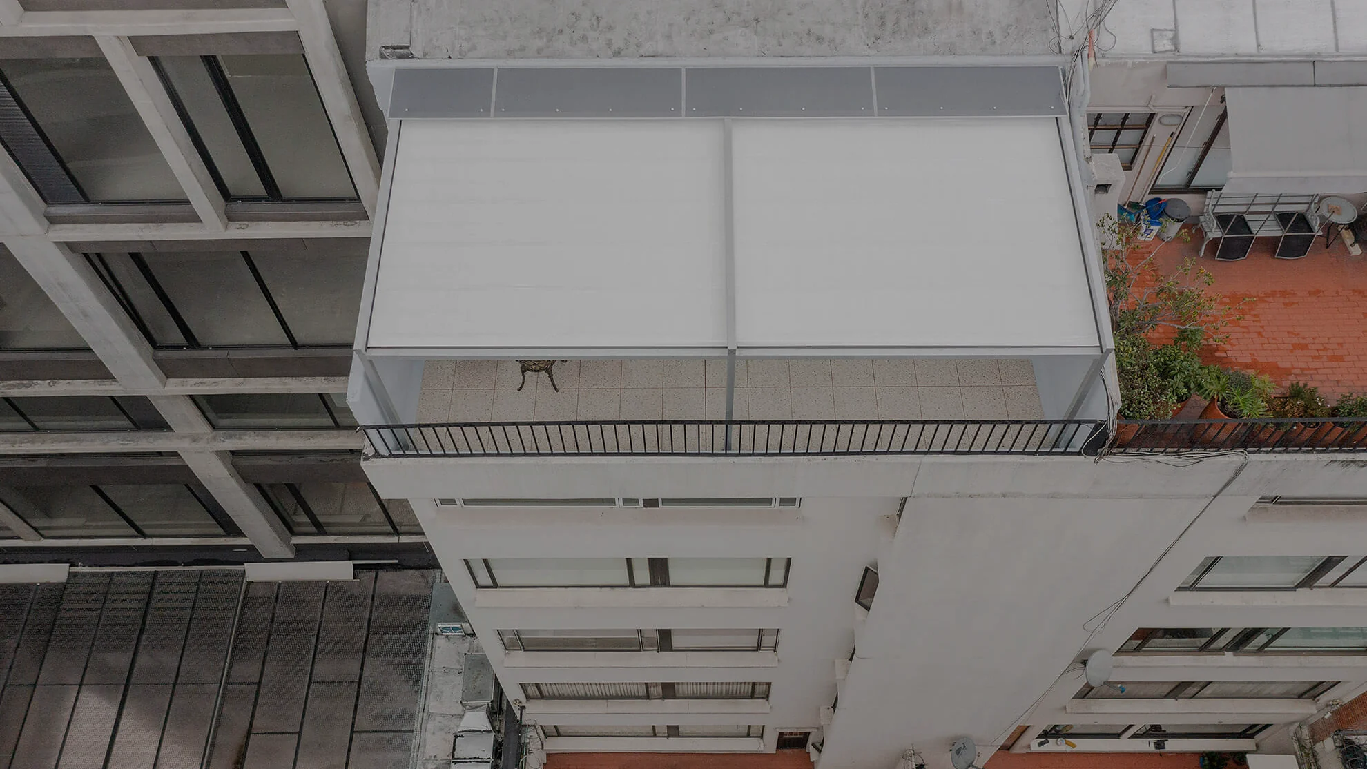 pérgola retráctil desplegada sobre el balcón de un apartamento, vista desde el piso superior