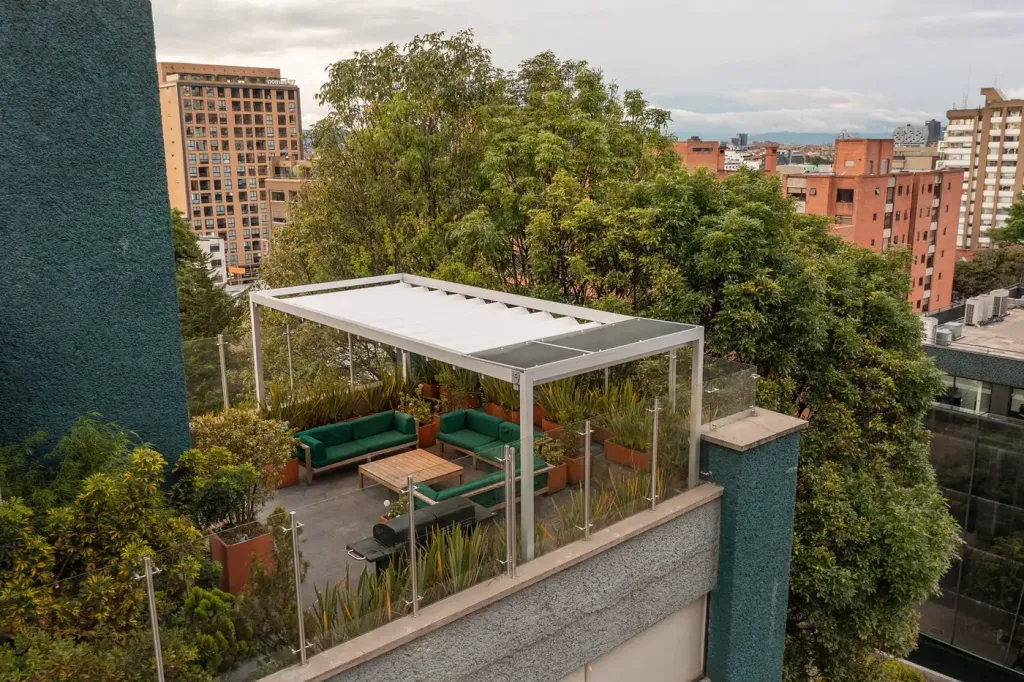 la pérgola retráctil vista desde arriba, sobre la última planta del edificio y entre el arbolado del barrio