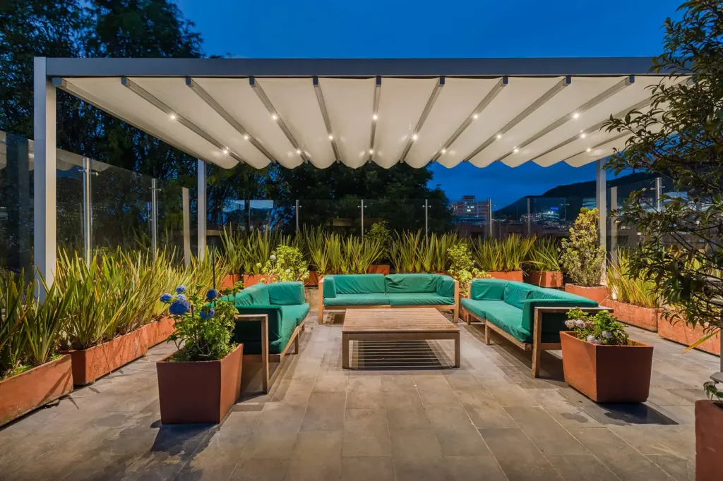 lona desplegada y luces LED de la pérgola retráctil sobre los sofás de la terraza, ya de noche