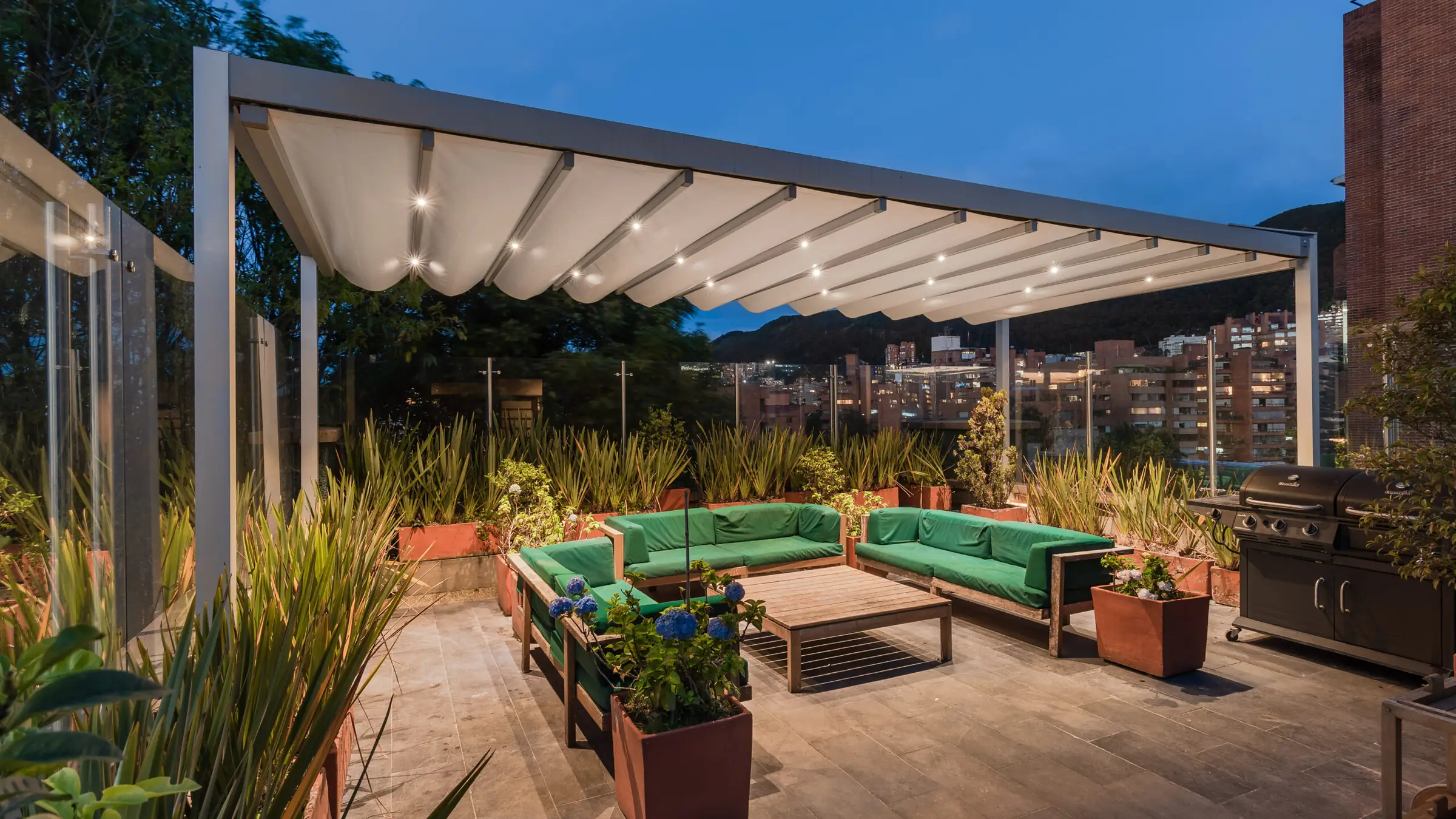 pérgola retráctil desplegada e iluminada al anochecer sobre la terraza social del Edificio Calle 76