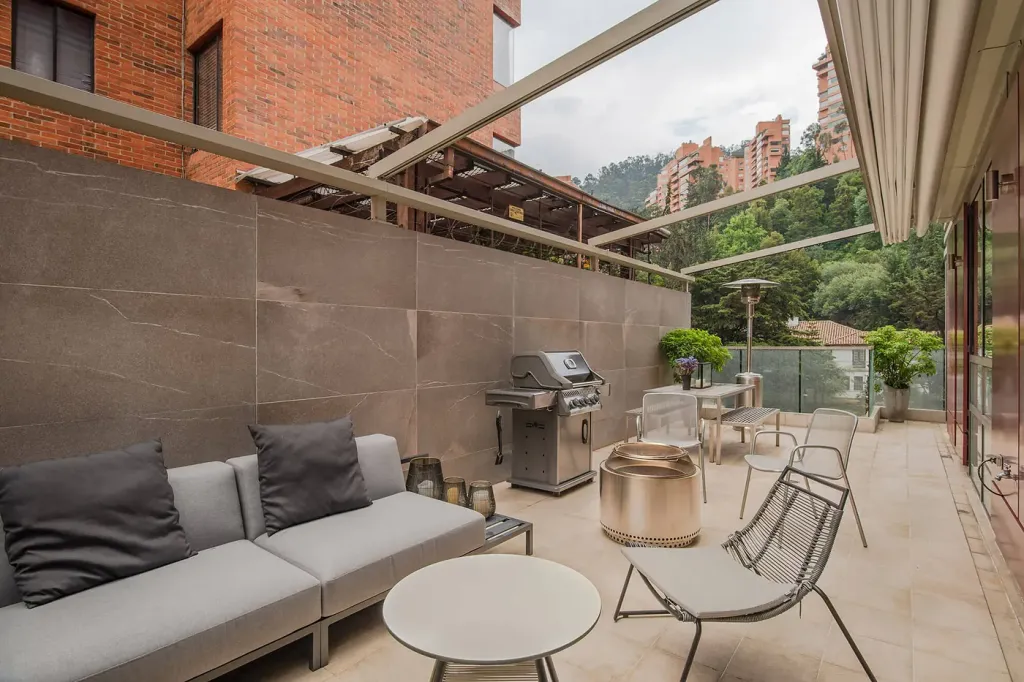 zona de estar de la terraza con la pérgola retráctil recogida y los cerros de Bogotá al fondo