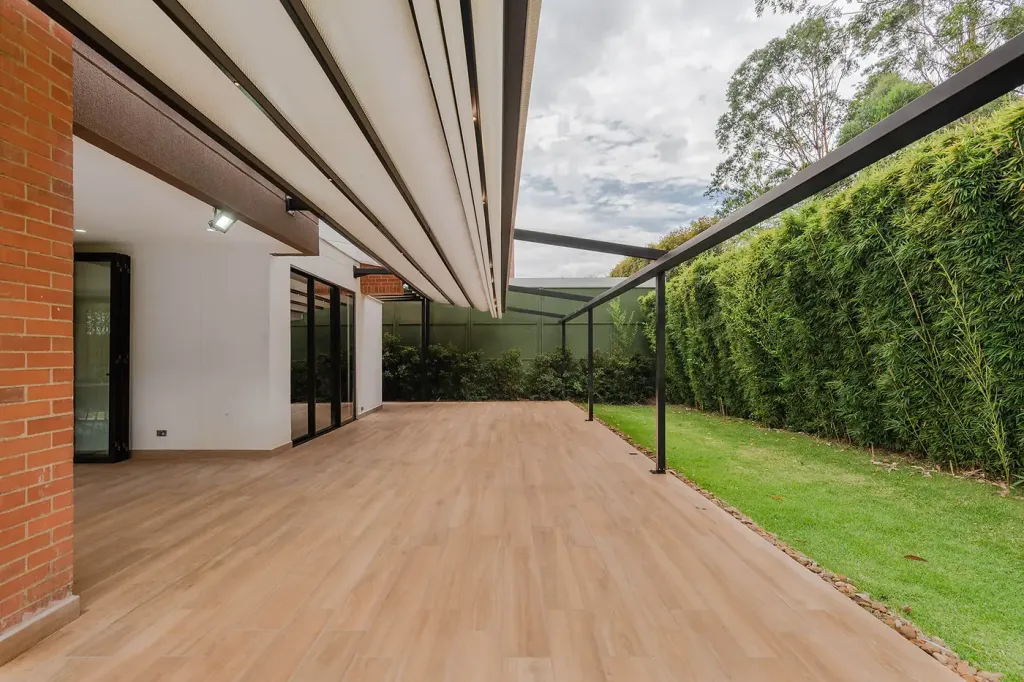 pérgola retráctil desplegándose sobre el deck en madera de una casa campestre