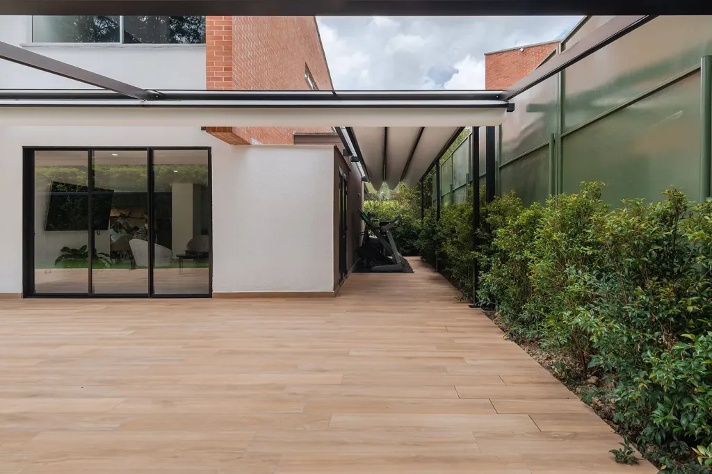 pérgola retráctil siguiendo la fachada de una casa campestre sobre un deck en ele