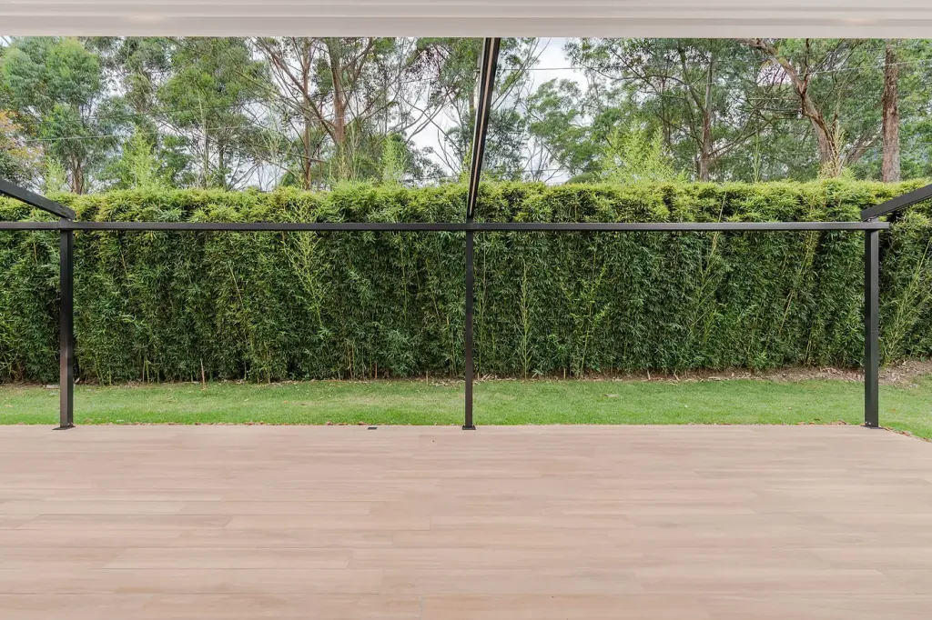 estructura de una pérgola retráctil con la lona recogida, vista desde el jardín de una casa campestre