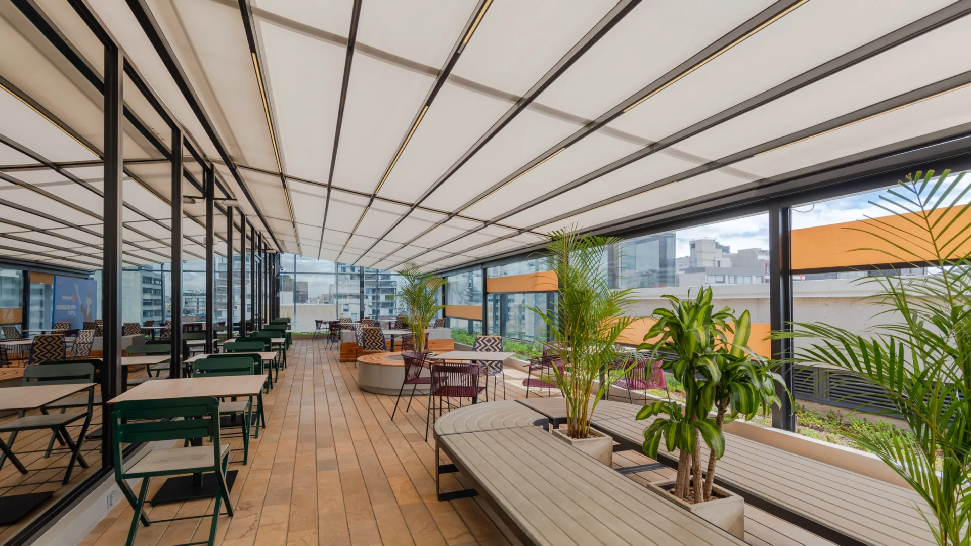Pérgola retráctil de lona tensa sobre terraza corporativa con cerramiento en vidrio