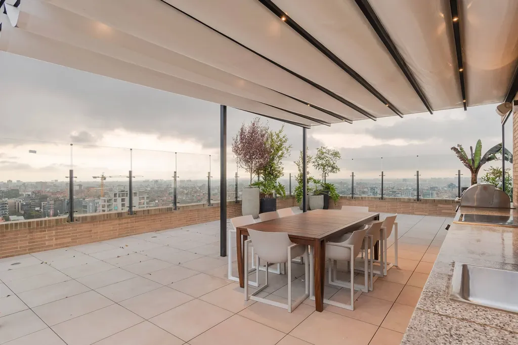 comedor exterior bajo la cubierta desplegada de una pérgola retráctil en una terraza