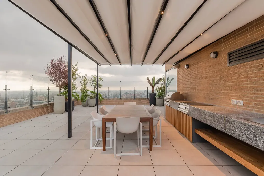 cubierta desplegada de una pérgola retráctil sobre el comedor y el asador de la terraza