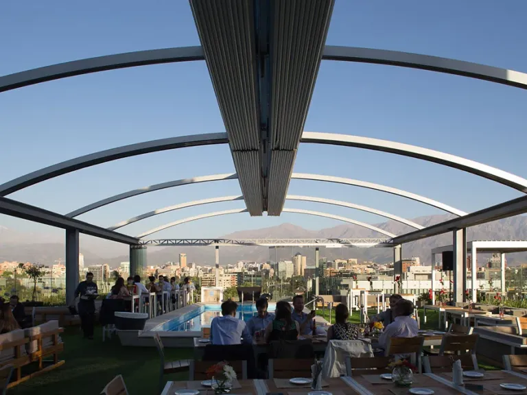 Pérgola retráctil PergoDom sobre la terraza de un restaurante, con la lona recogida y el arco a la vista