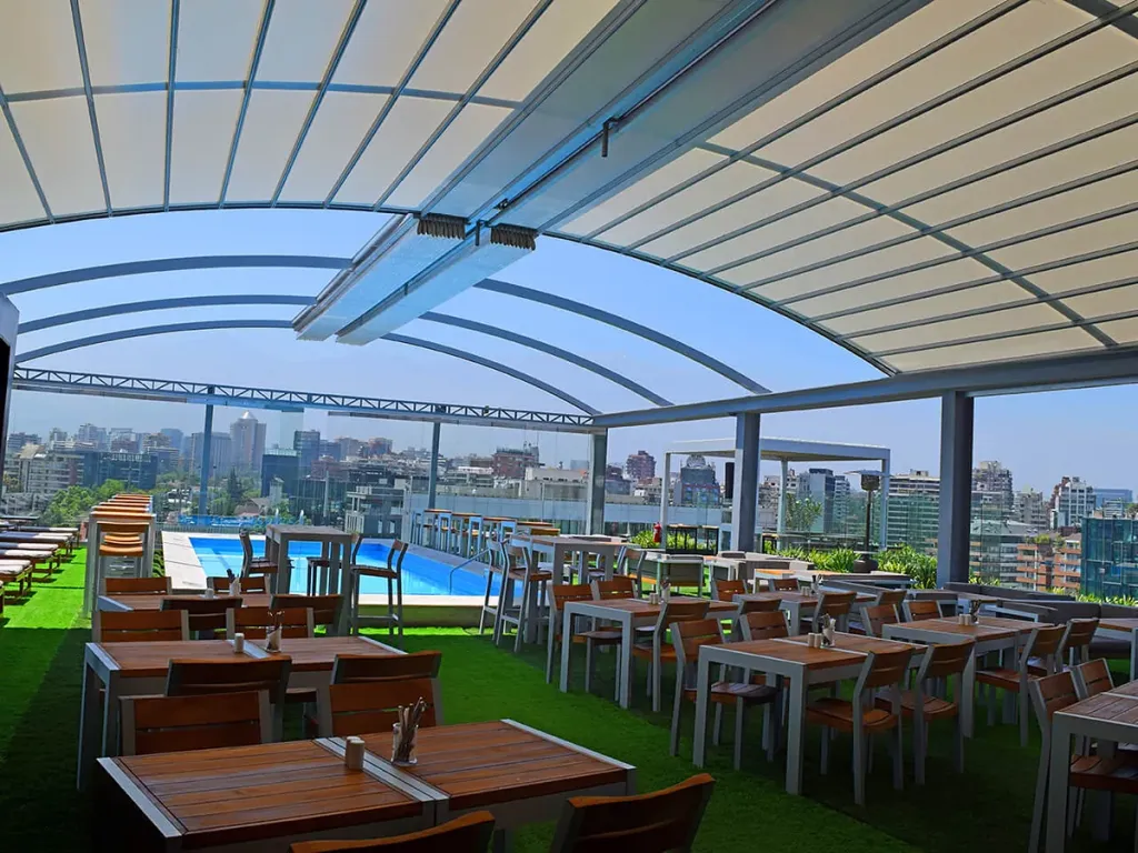 Pérgola retráctil PergoDom de perfiles curvos sobre el restaurante en el rooftop de un hotel, junto a la piscina