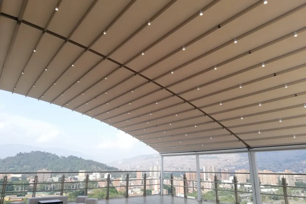 Salón cubierto con pérgola retráctil PergoDom de lona curva, con vista a las montañas
