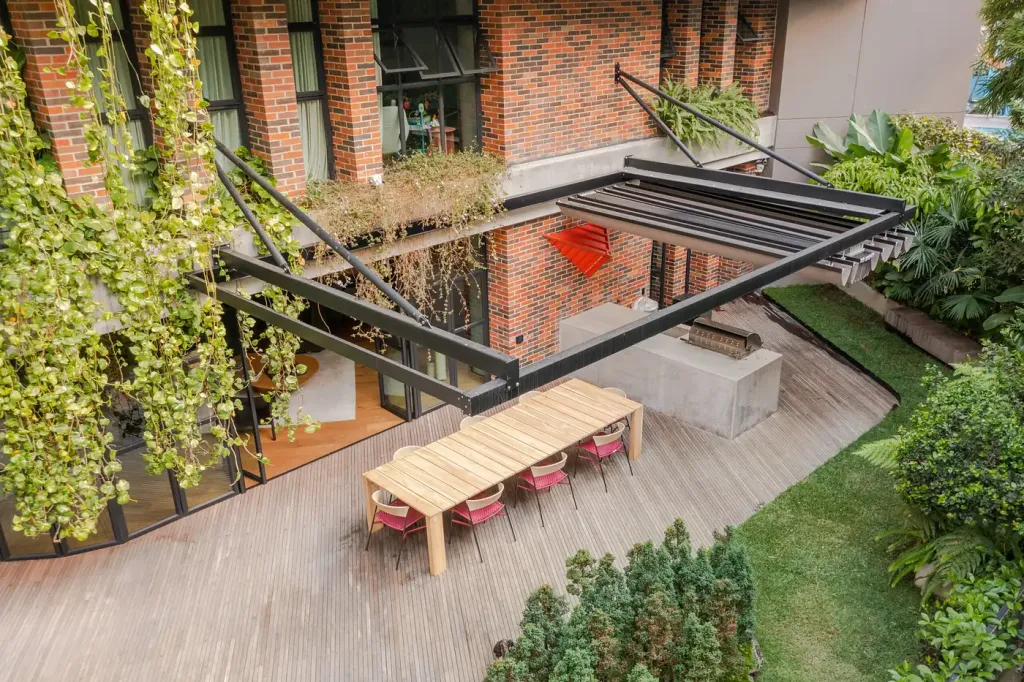 Pérgola retráctil PergoFlex anclada con tensores sobre el patio de una vivienda, vista de dron