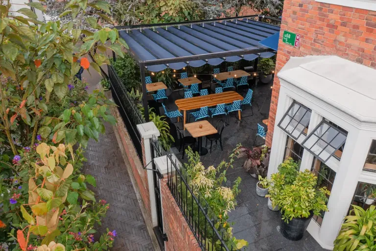 Pérgola retráctil PergoFlex sobre un patio de comidas estrecho entre medianeras, vista desde arriba