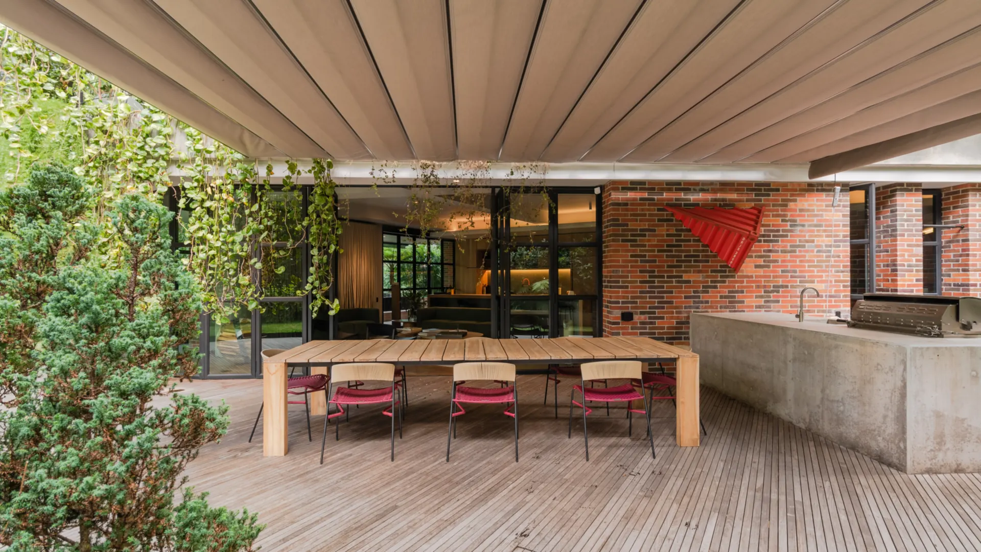 Pérgola retráctil PergoFlex con la lona extendida en pliegues sobre el comedor exterior de un patio residencial