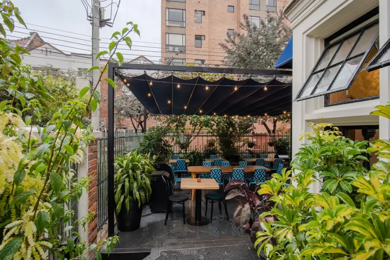 Pérgola retráctil PergoFlex de lona oscura sobre la terraza al aire libre de un restaurante