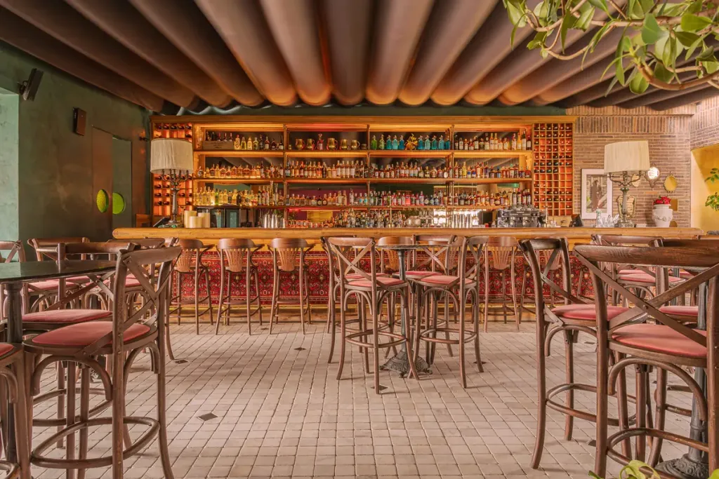 Barra de un bar bajo la palillería de una pérgola retráctil PergoTek