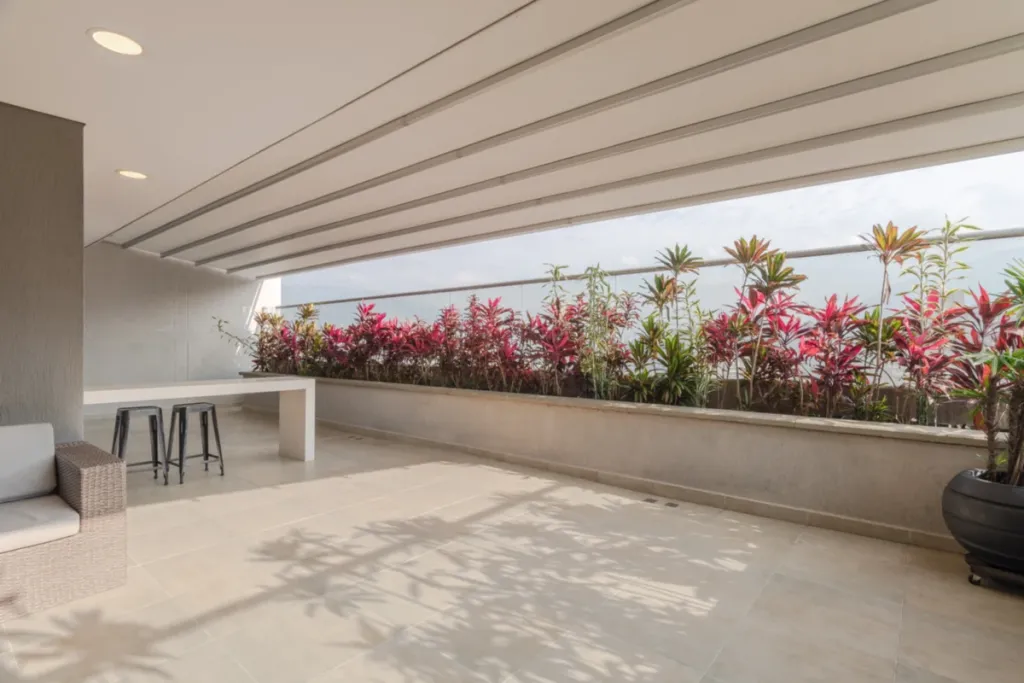 Corredor exterior cubierto con pérgola retráctil PergoTek junto a una jardinera de flores