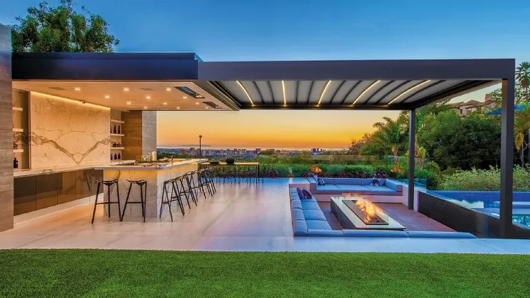Pérgola PergoTek Design sobre la barra de una terraza con chimenea, al atardecer